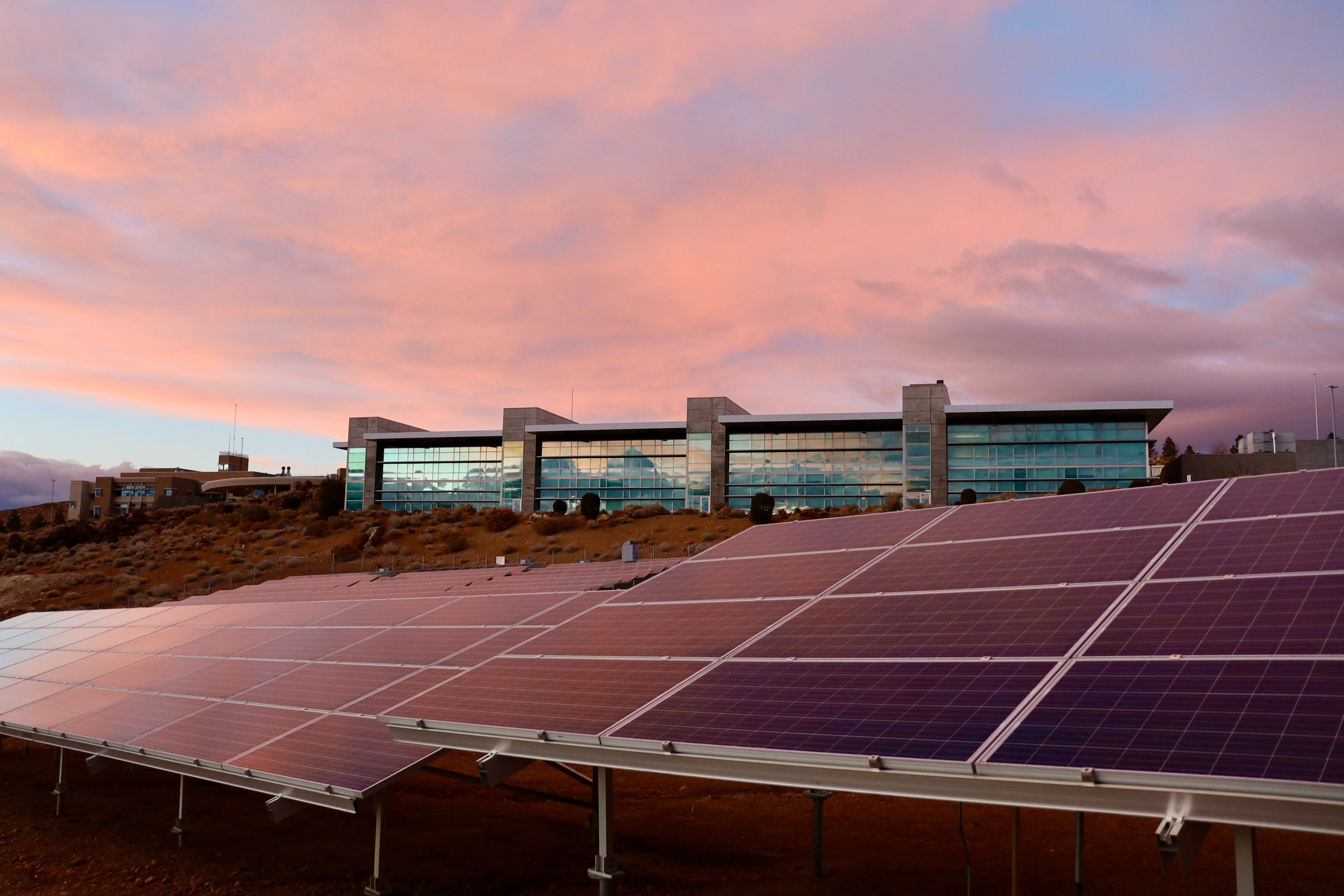 Ground mount solar panels in front of a large commercial building